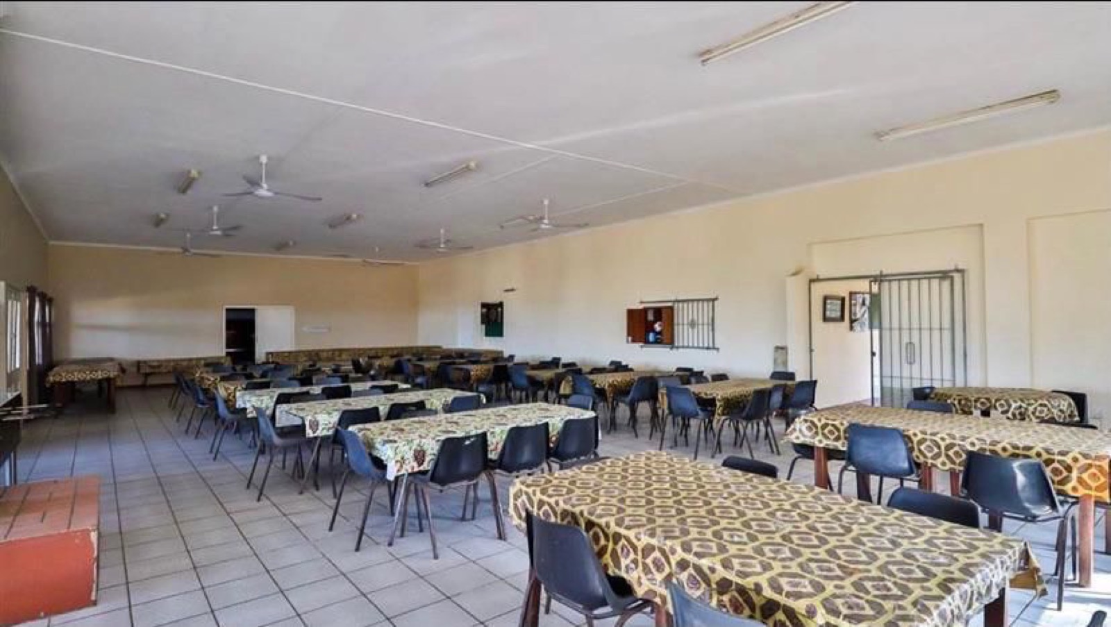 Tetelestai Recovery Centre communal dining hall set with rows of tables and chairs, ceiling fans, and tiled flooring