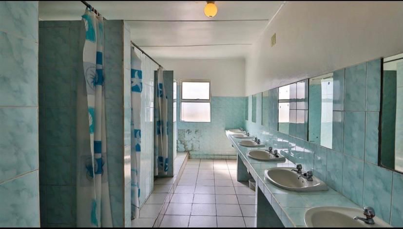 Tetelestai Recovery Centre clean communal bathroom and shower facilities with private shower stalls and multiple sinks