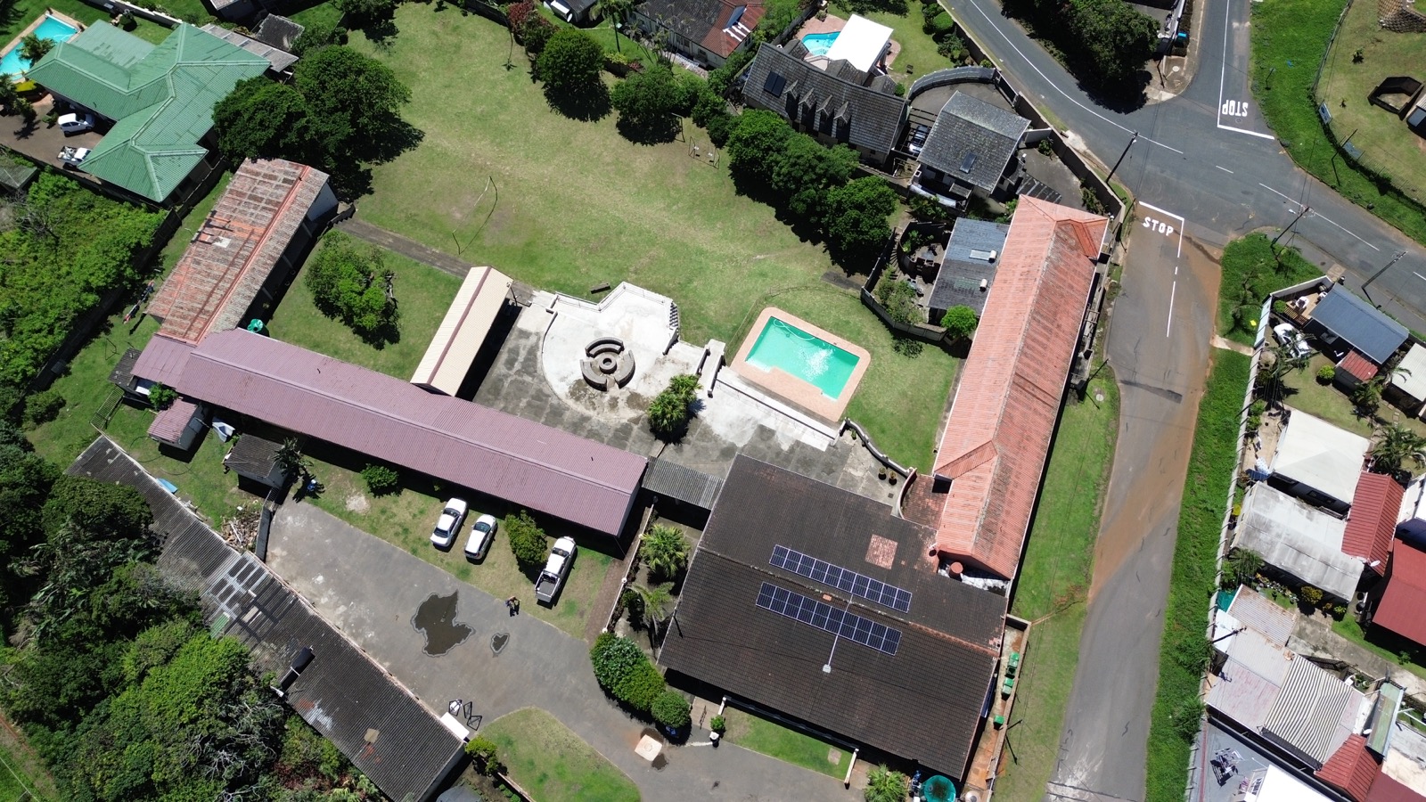Drone aerial photograph of Tetelestai Recovery Centre showing full property layout, solar panels, swimming pool, large lawn, and surrounding residential neighbourhood